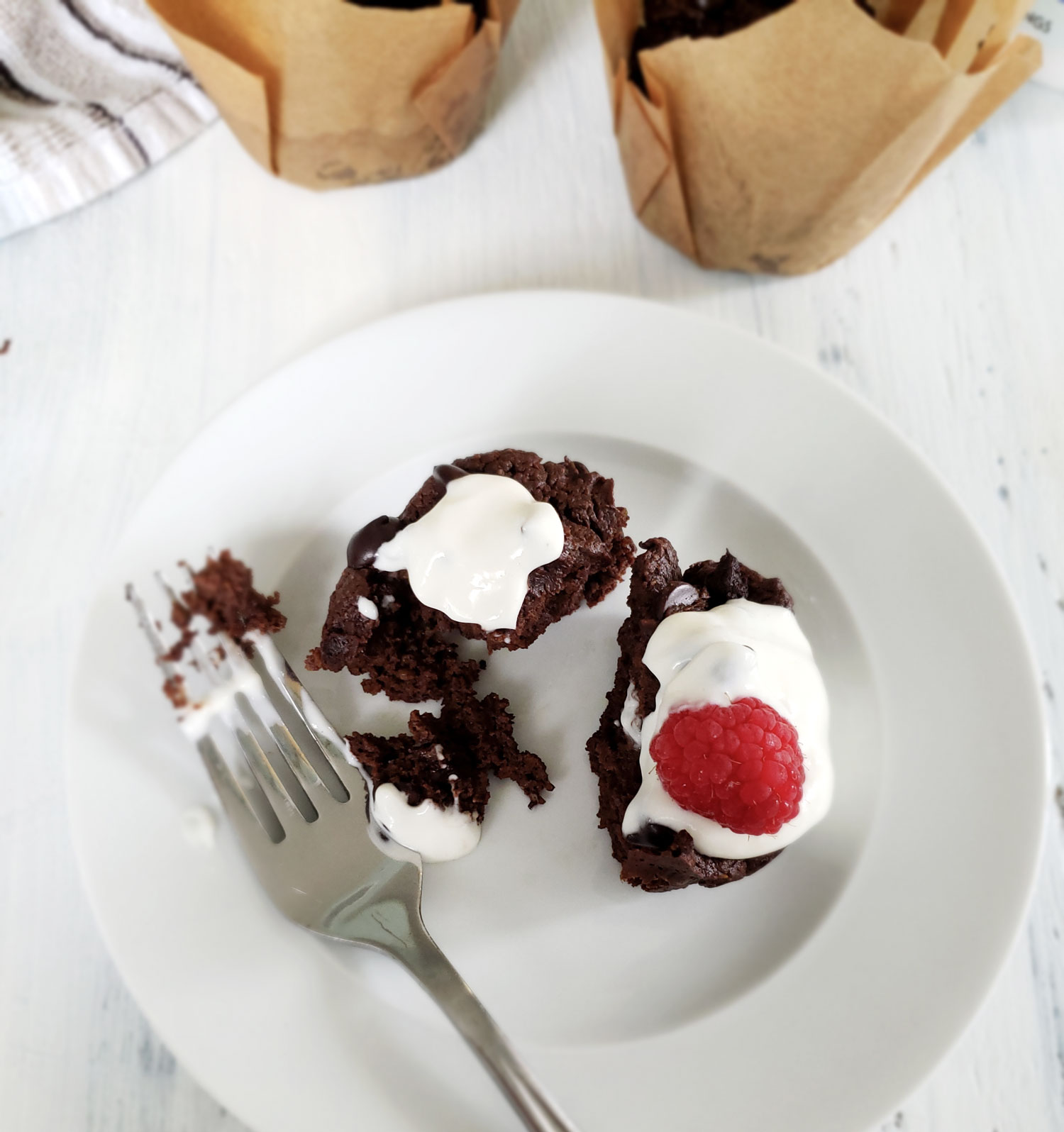 Double chocolate avocado cupcakes with Garden of Life Grass Fed Collagen and Greek Yogurt topping garnished with a red raspberry.