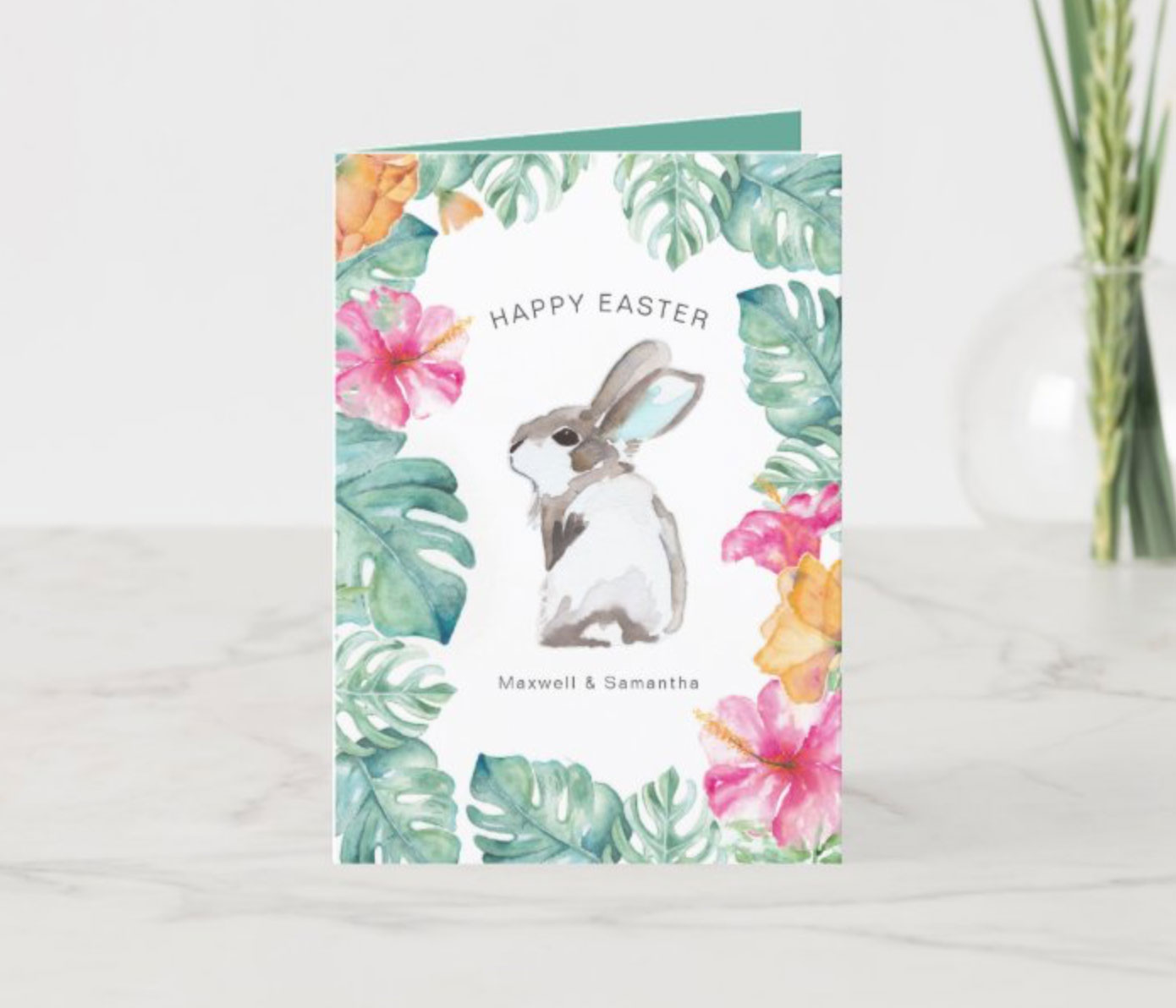 Tropical watercolor Easter cards designed by Victoria featuring a cute rabbit surrounded by monstera palm leaves and tropical pink and orange flowers.