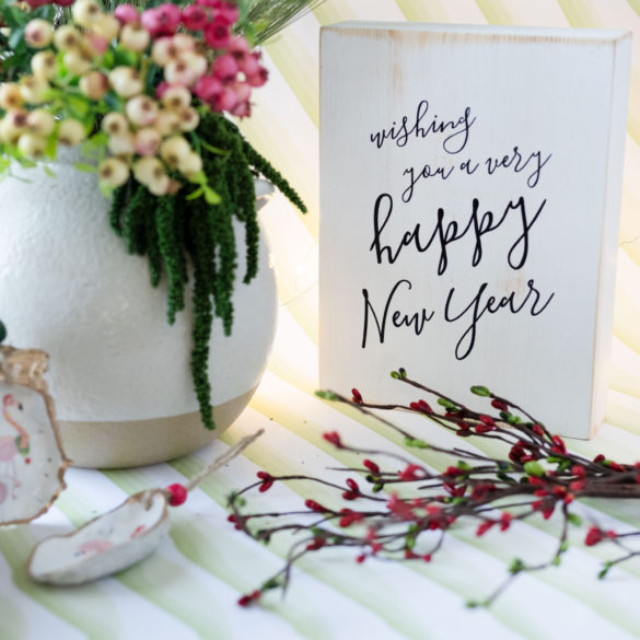 Christmas aesthetics for 2021. Cute holiday decor featuring a wooden sign that says Happy New Year and some decoupage Christmas ornament shells.