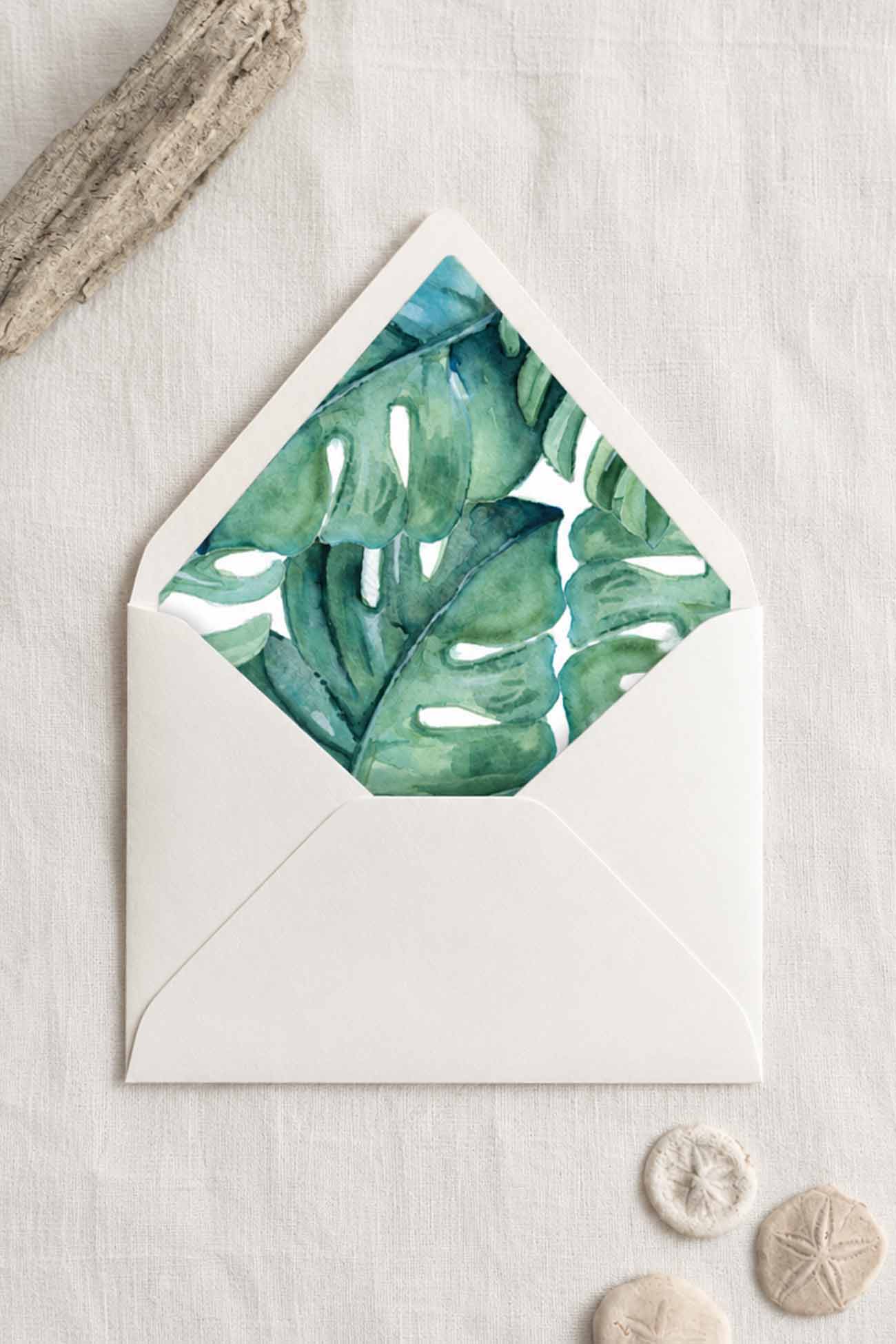 Tropical wedding envelope with original green watercolor monstera leaf liner on ivory stationery.