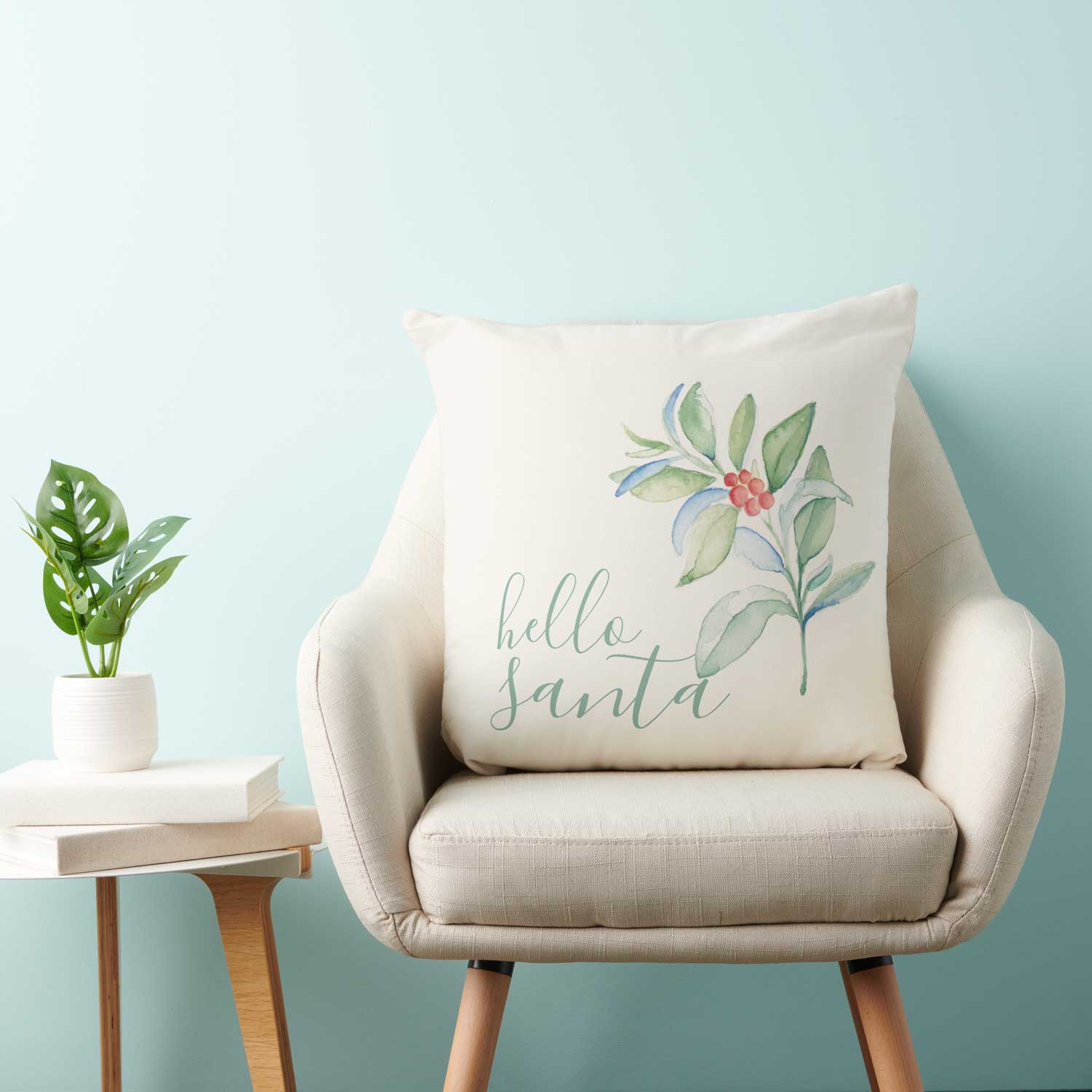 Christmas pillows feature the words "hello santa" with a sprig of watercolor greenery and red berries. Click to shop this pillow.