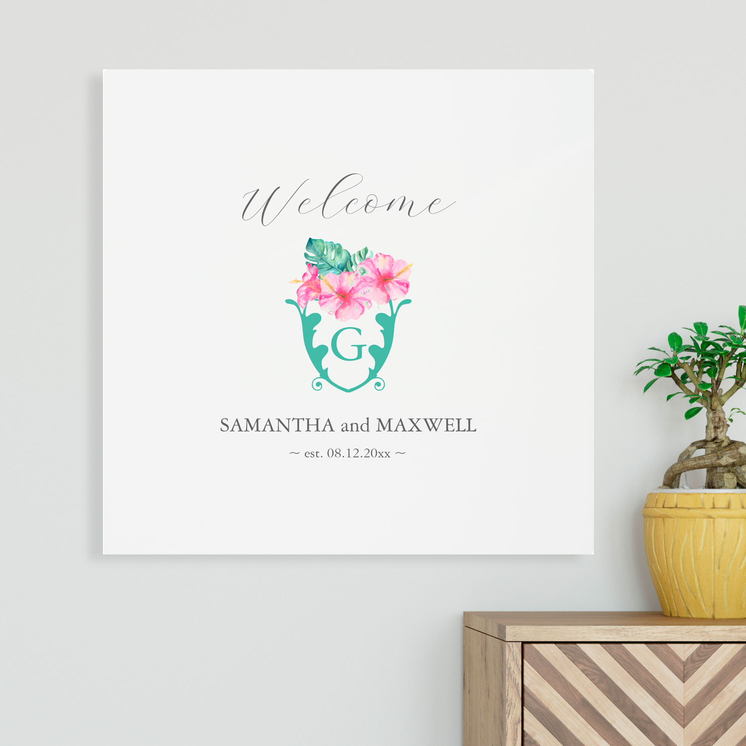 Tropical welcome sign features pink hibiscus flowers and monstera palm leaves. Personalize with you names and monogram. Click to shop.
