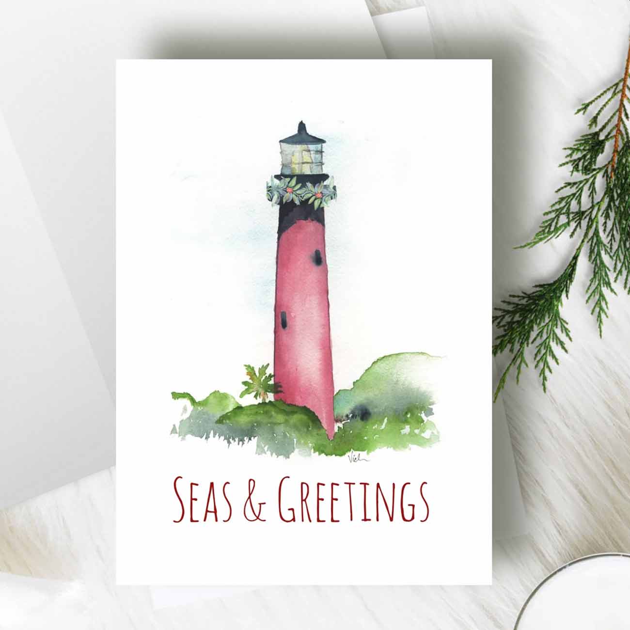 flat lay of nautical Christmas cards designed with the Jupiter, Florida lighthouse by watercolor artist Victoria Grigaliunas of Do Tell A Belle a woman owned small business.