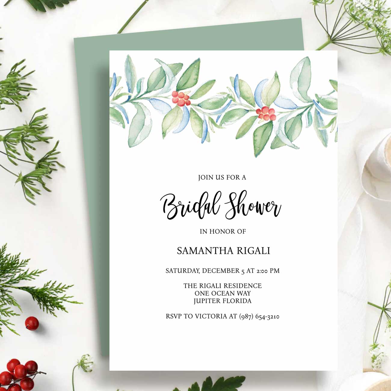Winter bridal shower invitations features watercolor botanical art in shades of green and red on a crisp white background by Victoria Grigaliunas of Do Tell A Belle a woman owned small business in South Florida