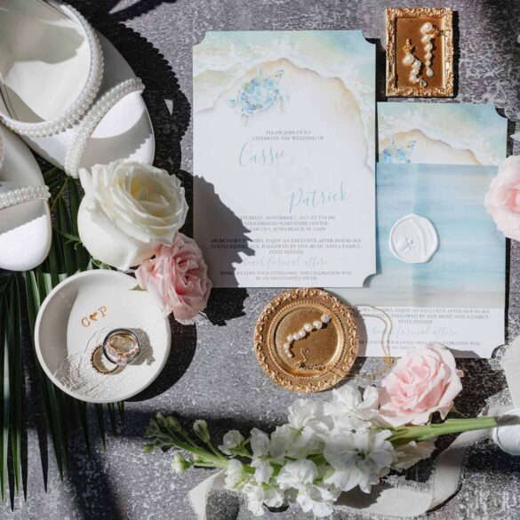A flat lay of a watercolor sea turtle wedding invitation suite for the Loggerhead Marinelife Center wedding venue. By Do Tell A Belle.