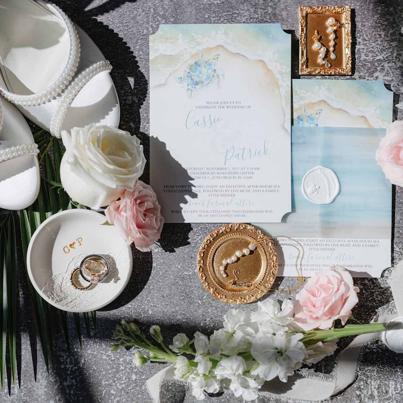 A flat lay of a watercolor sea turtle wedding invitation suite for the Loggerhead Marinelife Center wedding venue. By Do Tell A Belle.