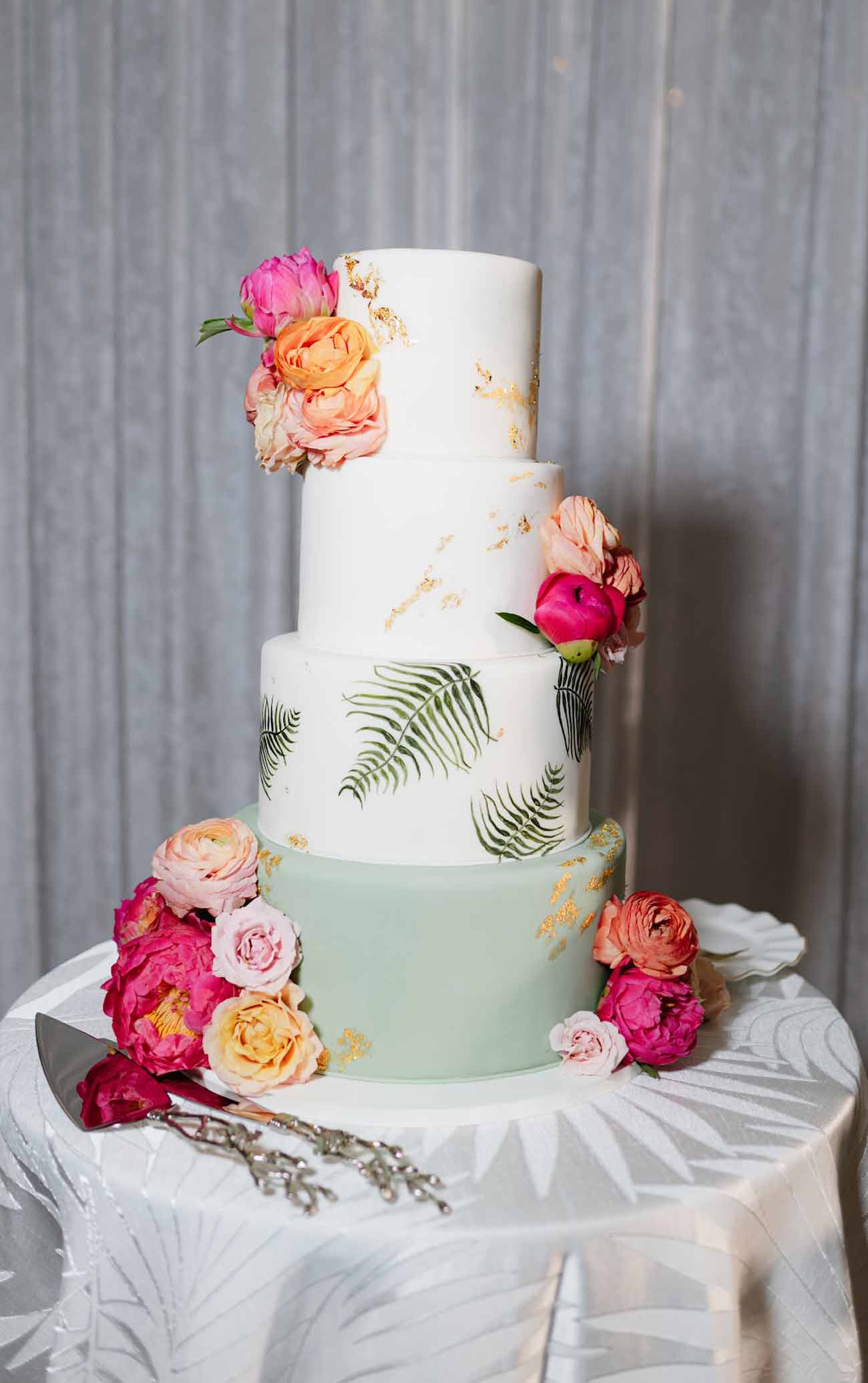 tropical wedding cake 4 tier with vibrant florals and palm leaves.