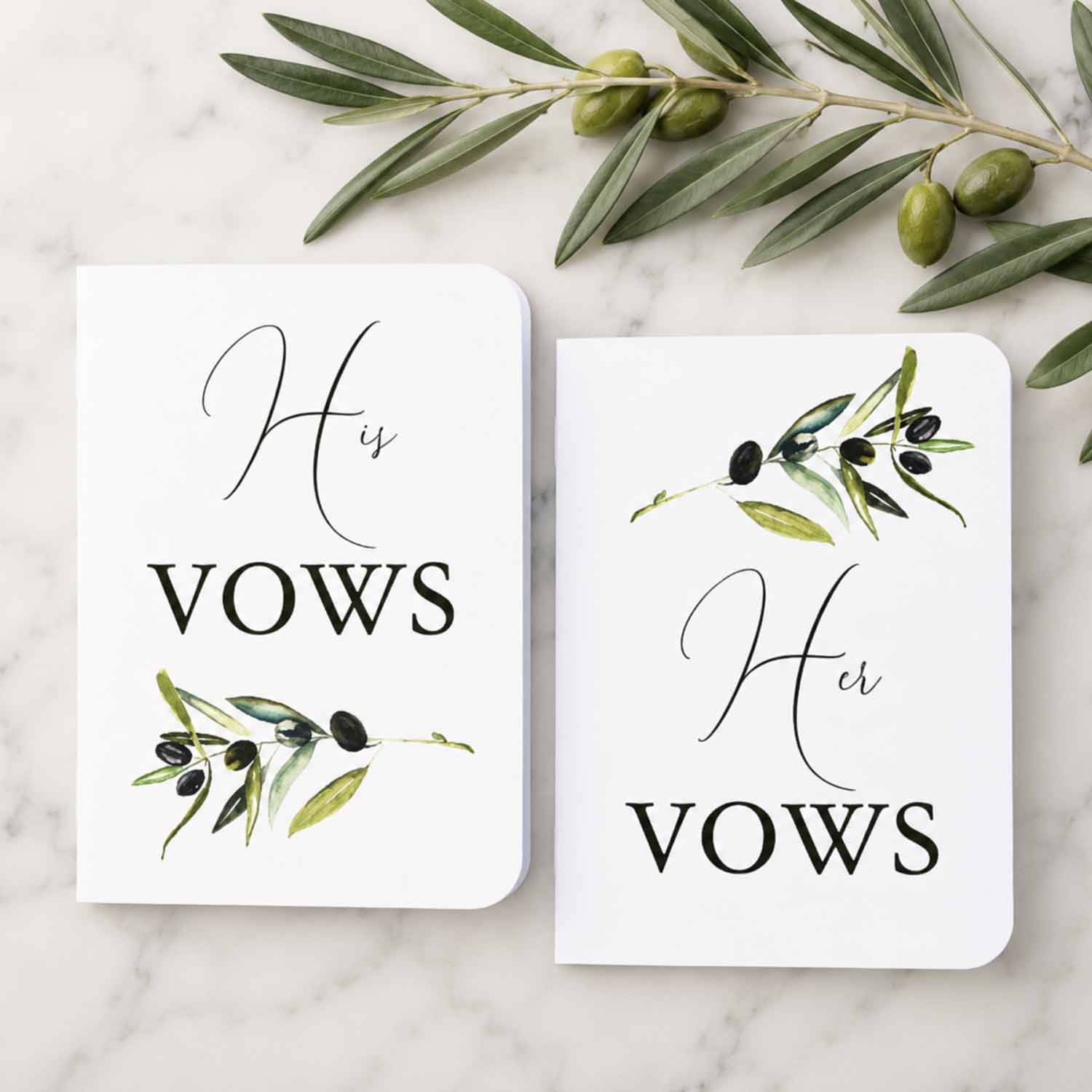 Wedding ceremony vows book set featuring personalized his and her vow booklets with watercolor olive branches styled on a marble surface for elegant rustic weddings.