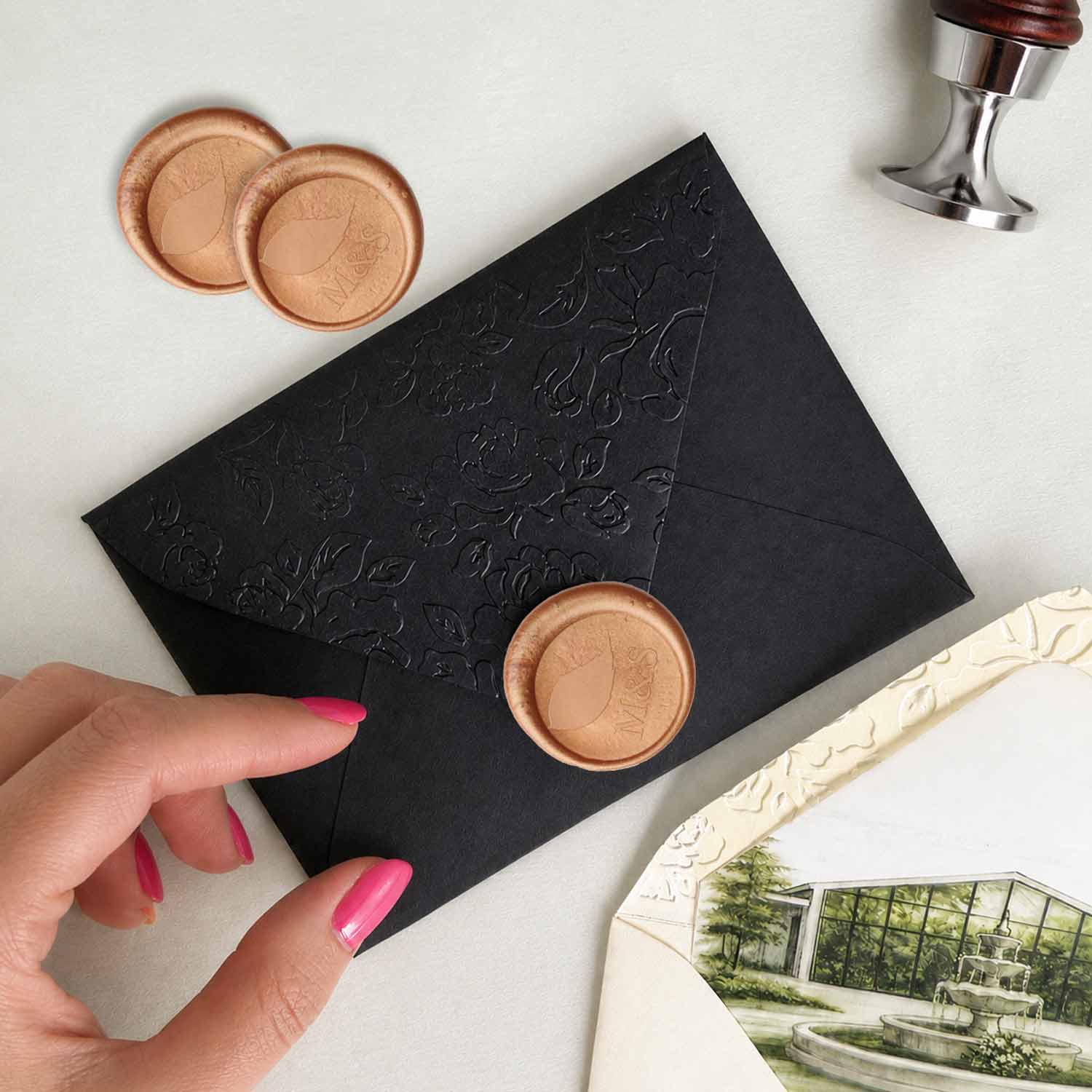 Custom ivory wax seal on wedding invitations featuring a personalized monogram, displayed on a black embossed envelope with luxury wedding stationery details.