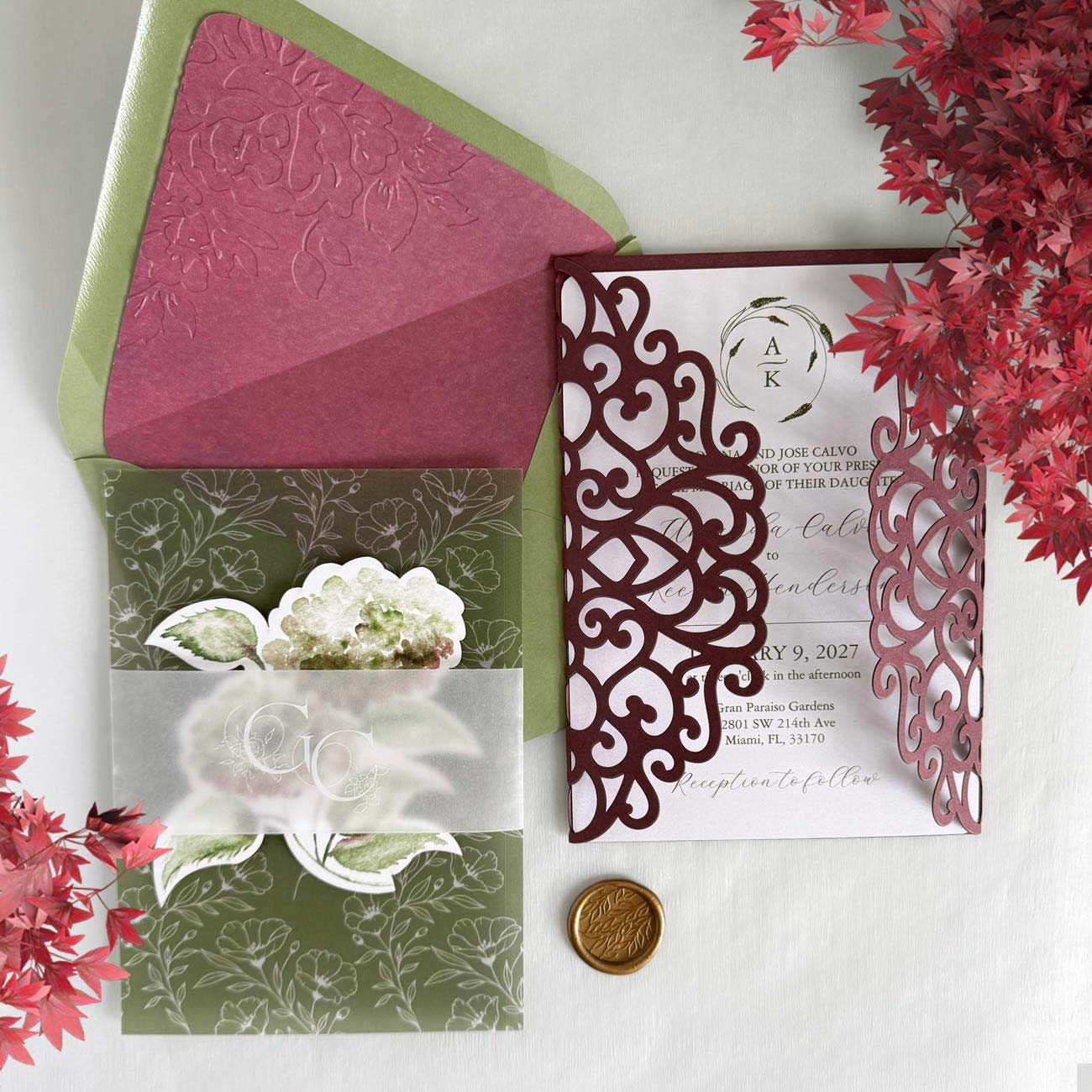 Unique wedding invitations featuring a burgundy and green laser-cut gatefold, embossed envelope liner, vellum inserts, and watercolor floral artwork.
