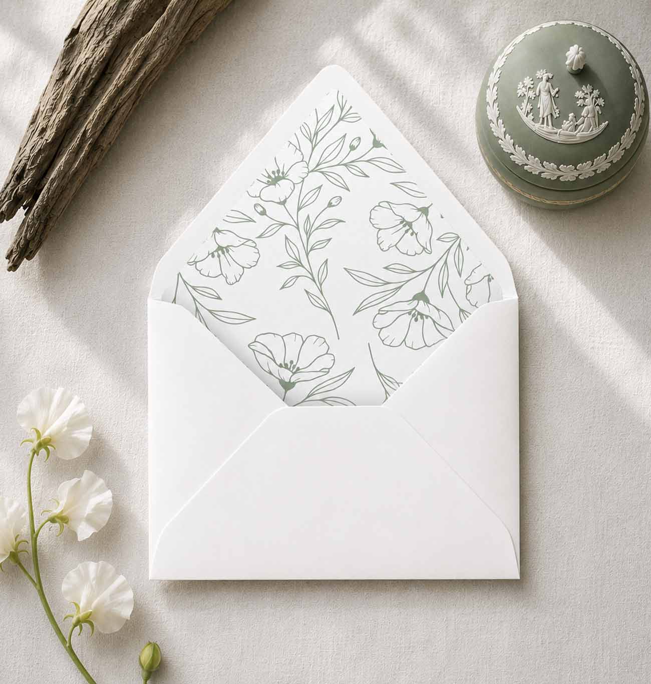 Sage green envelope liners with elegant floral line art installed inside white euro flap wedding envelopes for wedding invitations.