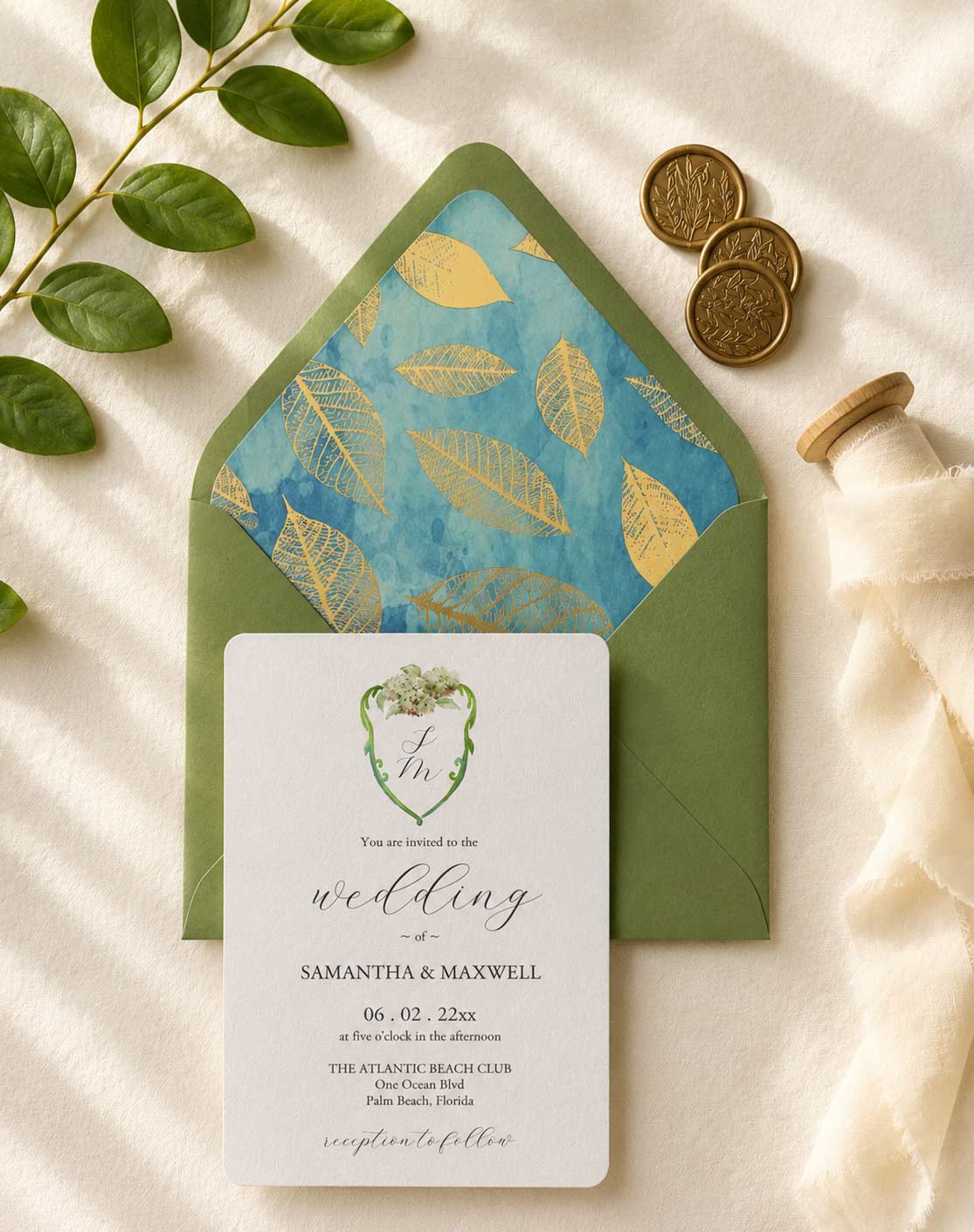 Watercolour crest wedding invitations with a custom green watercolor crest, hand-painted hydrangeas, green envelope, and turquoise blue envelope liner accented with gold foil leaves.