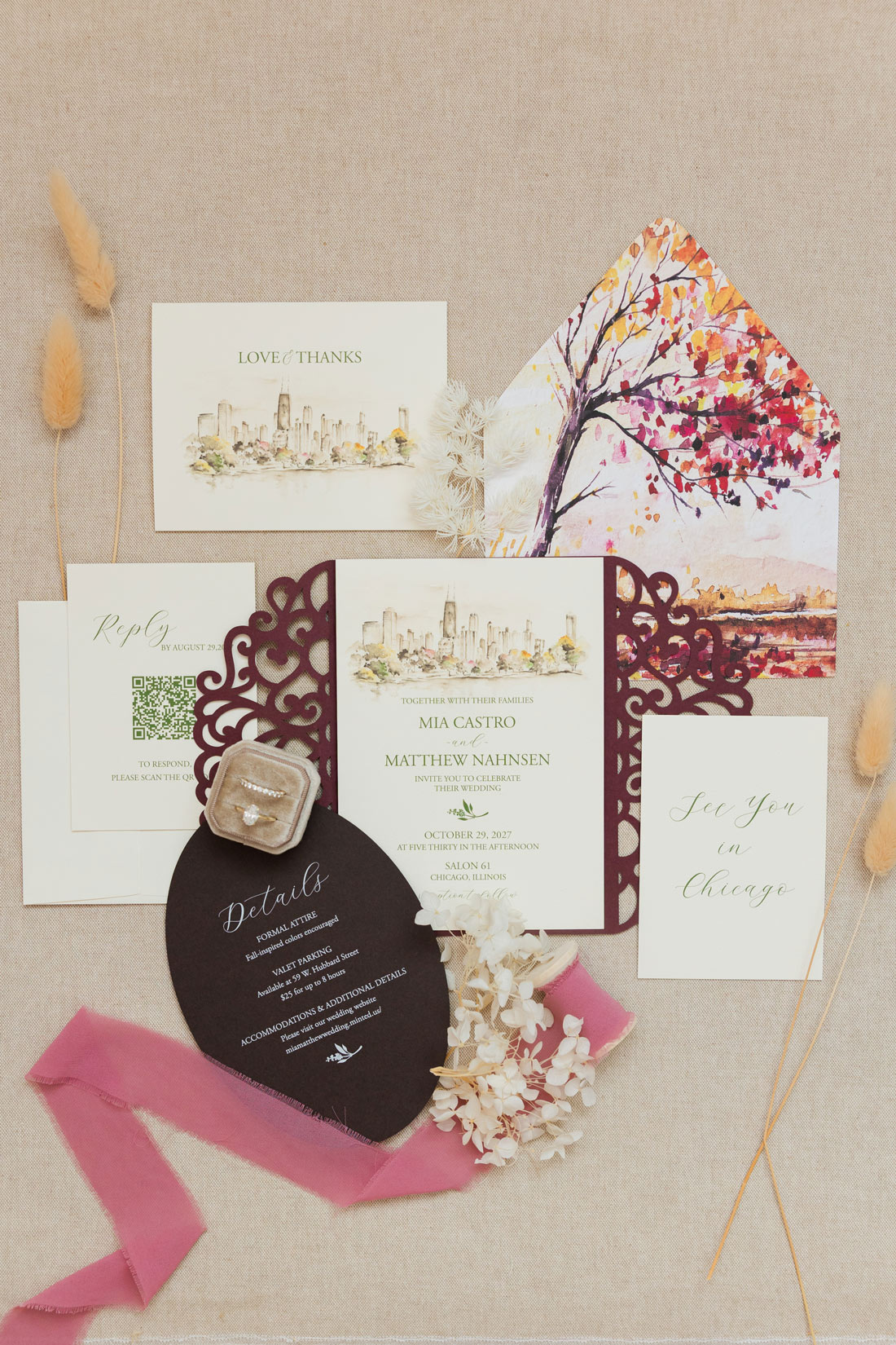 Flay lay of my watercolor Chicago skyline wedding invitation with burgundy laser-cut gate fold, fall watercolor envelope liner and coordinating details card.