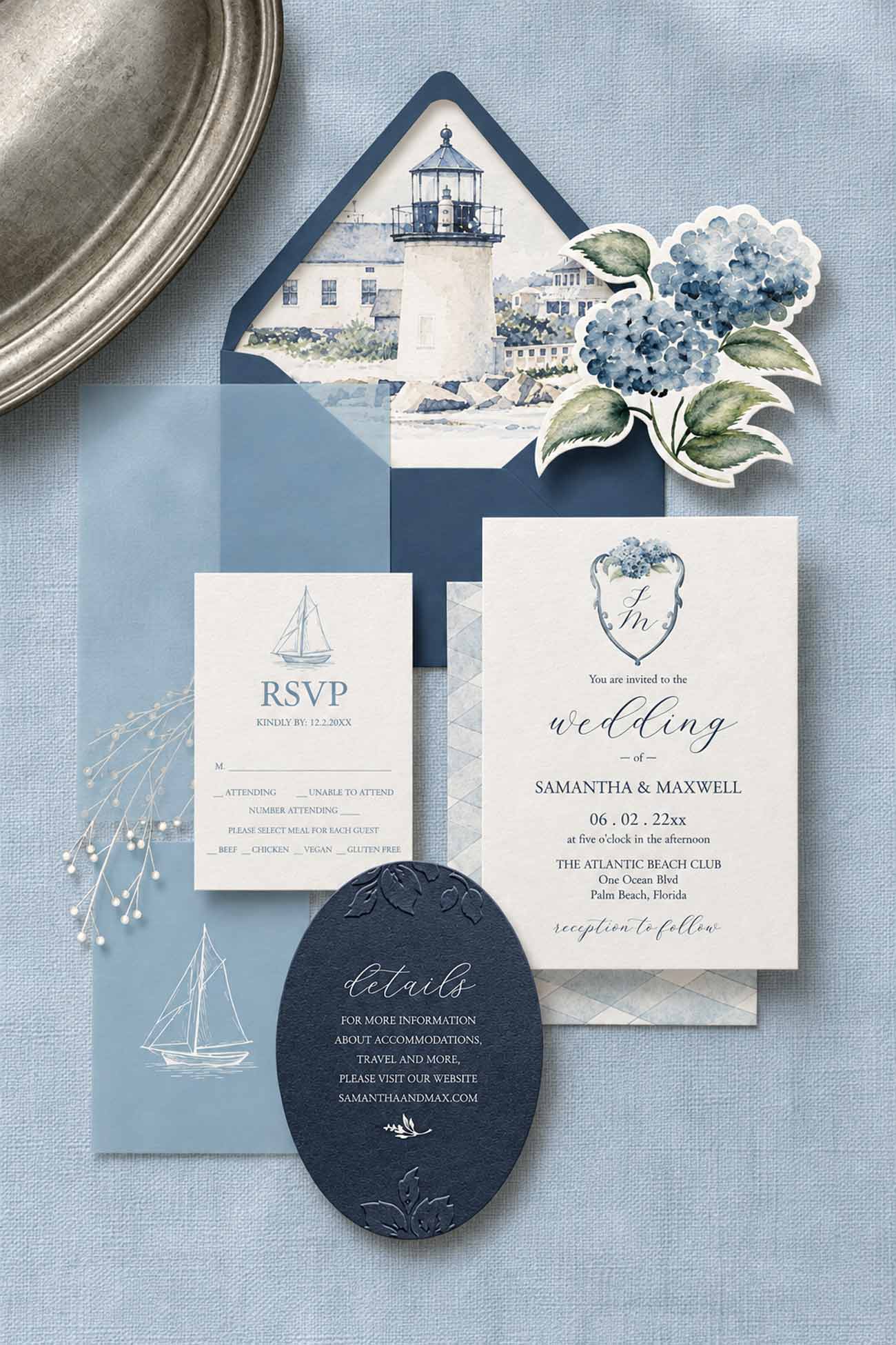 Coastal watercolor wedding invitation suite featuring a lighthouse envelope liner, embossed navy blue details card, sailboat RSVP, die-cut hydrangea illustration, and dusty blue wedding stationery.